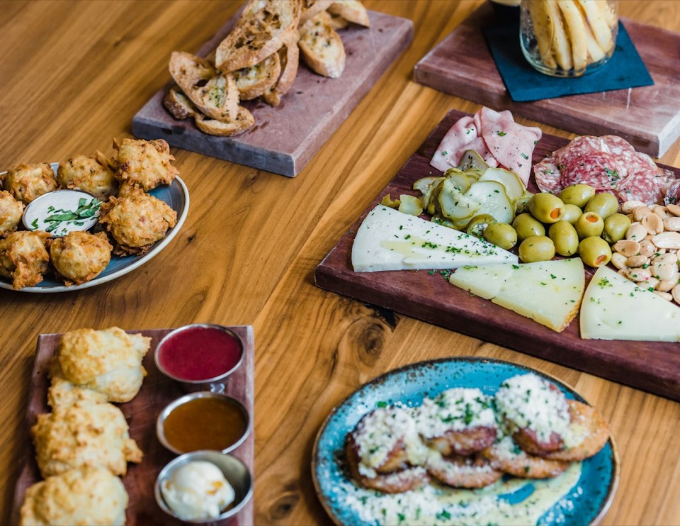 A table with fritters, cheese, olives and toast