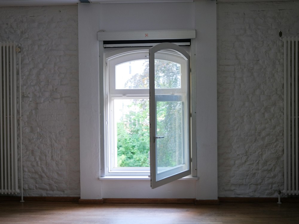 White brick wall with an open window and two old radiators either side