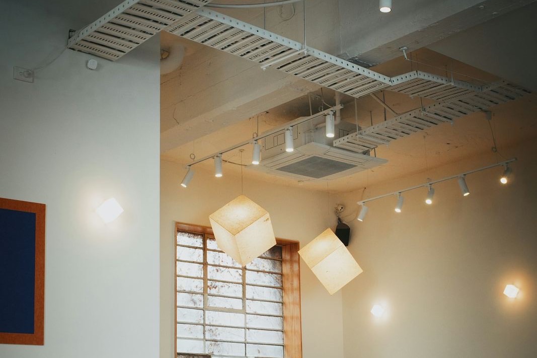 Café ceiling with a cassette unit between cable trays, spotlights and pendant lamps
