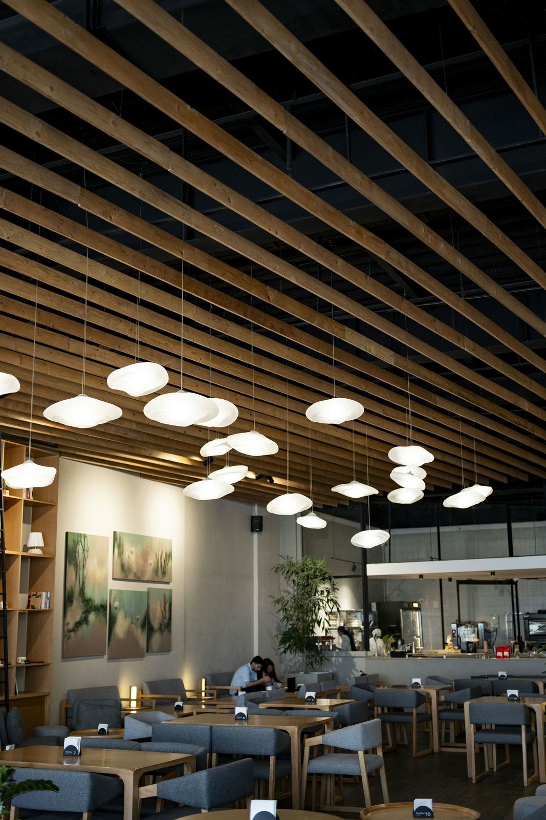 Restaurant with a wooden slatted ceiling, pendant lamps and tables