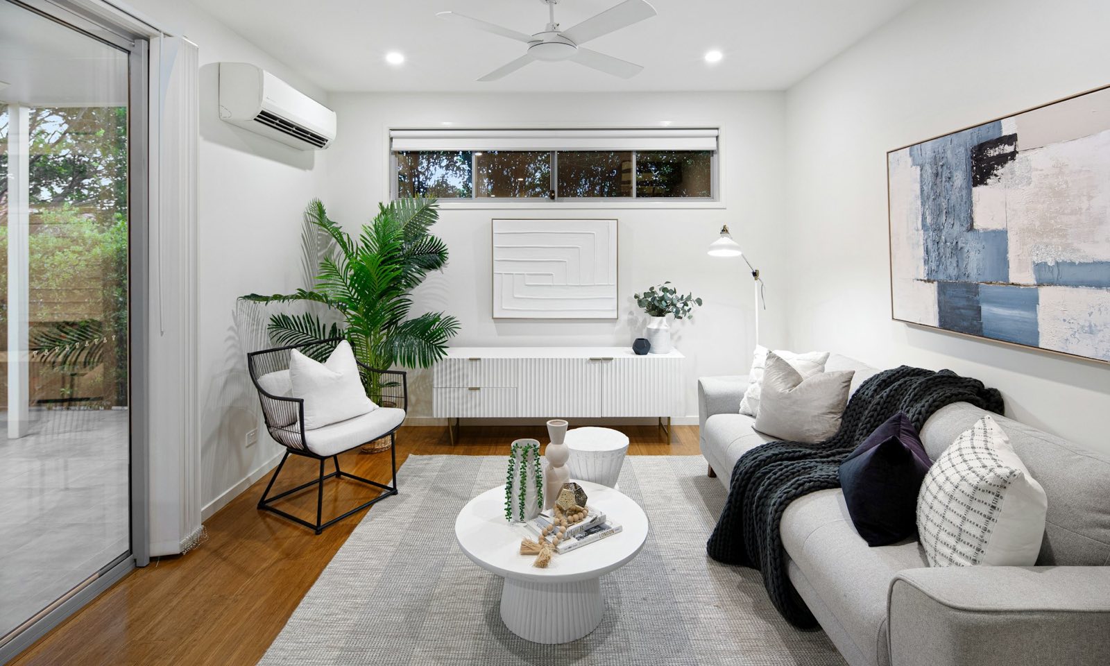 Bright living room with a white split unit on the wall near the ceiling, above the door to the terrace
