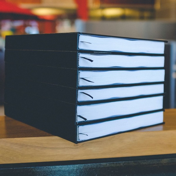 Six theses in black hardback bindings, stacked on a table