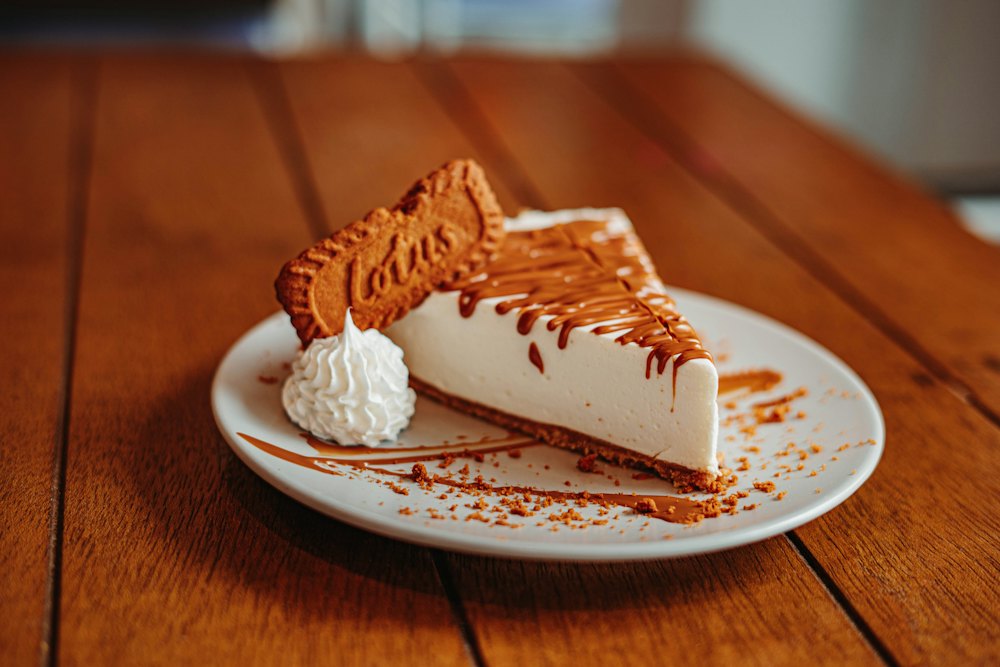 A slice of cheesecake with a caramelised biscuit and a little whipped cream