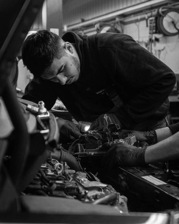 Mechanic leaning over the engine, checking the connectors