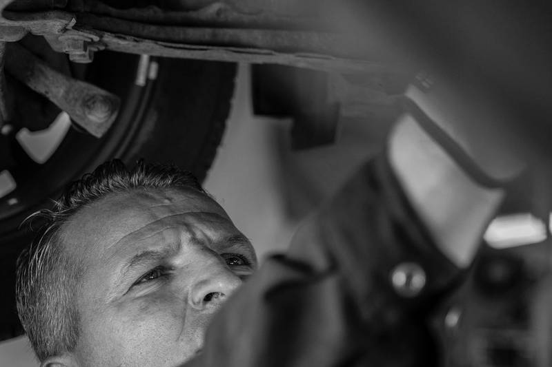 Mecánico revisando los bajos del coche desde abajo